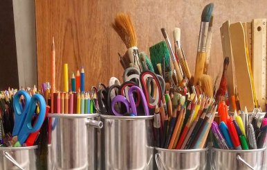 Tarros de metal llenos de diversos implementos escolares