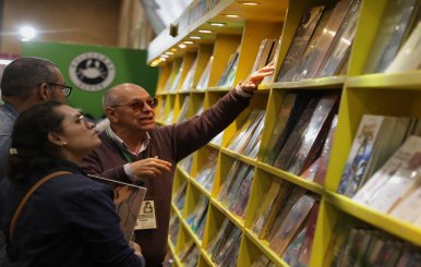 Personas mirando libros en una estantería en la Filbo