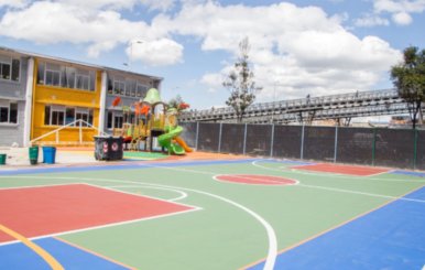 Patio principal de un colegio de Bogotá con una cancha de microfútbol pintada de verde, rojo y azul.