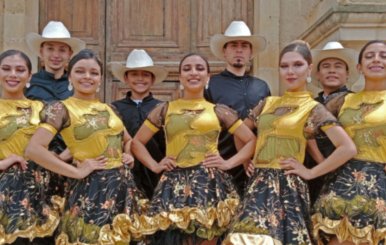 Hombres y mujeres con trajes típicos: mujeres con vestidos dorados y negros y hombres con camisas negras y sombreros