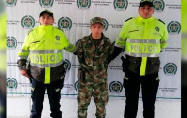 Dos oficiales de Policía, con un hombre capturado vestido con uniforme militar