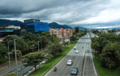 Carretera con pocos carros transitando y rodeada de árboles