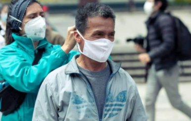 Mujer poniéndole un tapabocas a un hombre de mediana edad