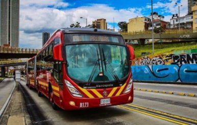 Bus de TransMilenio, color rojo, rodando por la calle 