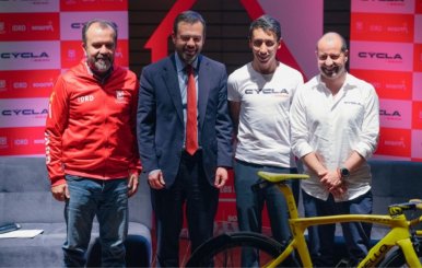 Cuatro personas posando en una tarima atrás de una bicicleta amarilla