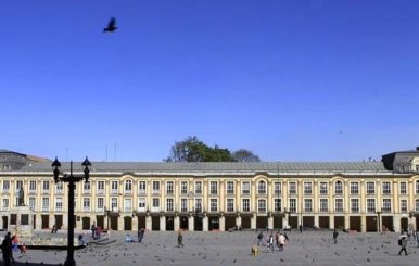 Edificio de color blanco con muchas ventanas. Arriba se ve el cielo azul