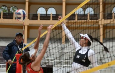 Dos mujeres disputando un balón de voleibol. 