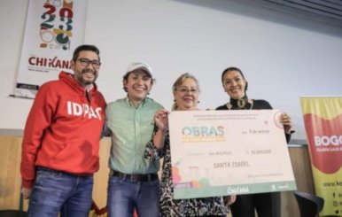 Funcionarios de la Alcaldía de Bogotá junto a beneficiarias del Fondo Chikaná, que sostienen un cheque en sus manos
