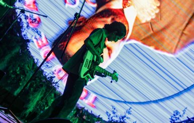 Músico con una guitarra sobre una tarima 