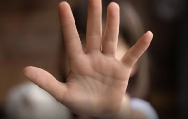 Niña poniendo su mano al frente para tapar su cara