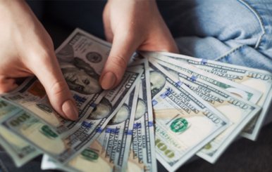 Unas manos sostienen entre ocho y nueve billetes de un dólar