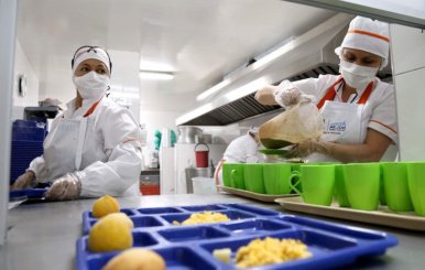 Cocineras sirviendo comida en bandejas de plástico