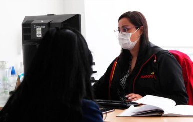 Mujer con tapabocas frente a un computador