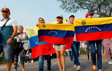 Personas caminando con la bandera de Venezuela
