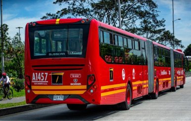 Bus de TransMilenio, color rojo, rodando por la calle 