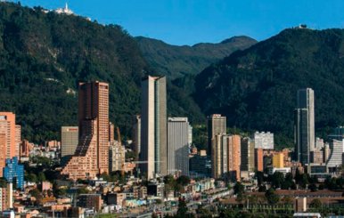 Edificios, rascacielos y casas en una vista panorámica. Una montaña grande atrás.