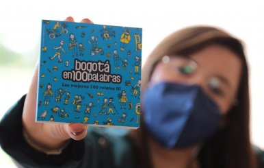 Una mujer sosteniendo un ejemplar de Bogotá en cien palabras.