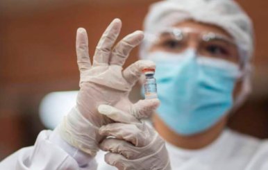 Personal de salud sostiene un tarro con el líquido de la vacuna contra covid-19