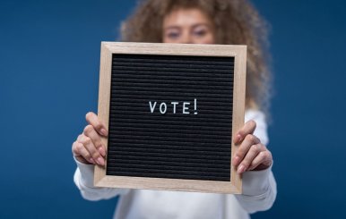 Niño sostiene un tablero con la palabra Voto