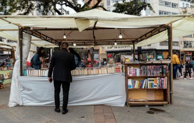 Hombre viendo un puesto con muchos libros en una Feria Popular de Bogotá