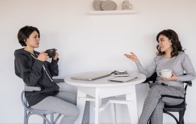 Dos mujeres conversando en una mesa mientras toman un café