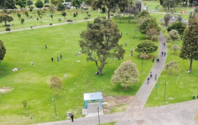 Vista aérea de un parque de Bogotá con zonas verdes y un pasillo de tránsito. 