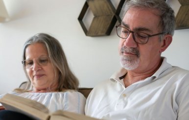 Dos adultos mayores leyendo libros en un sillón
