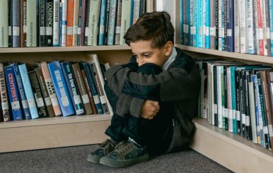 Niño triste en un rincón de un escaparate con libros