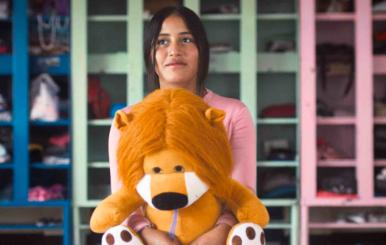 Niña abrazando un peluche en forma de león 