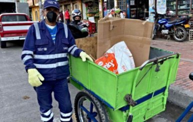 Uno de los recicladores de Bogotá junto a una carretilla y material reciclable 