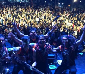 Una banda posando detrás de un público lleno de personas